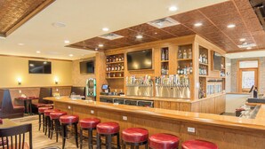 A bar area with stools, a counter, and a selection of bottles. - Holiday Inn Trophy Club by IHG (Roanoke)