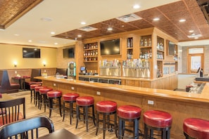 Een bar met krukken, een toonbank en een assortiment flessen.