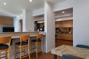 Una cocina moderna con armarios de madera, estufa integrada y una zona de bar con taburetes.