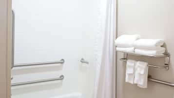 Um banheiro com banheira, cortina de chuveiro, vaso sanitário e porta-toalhas com toalhas.