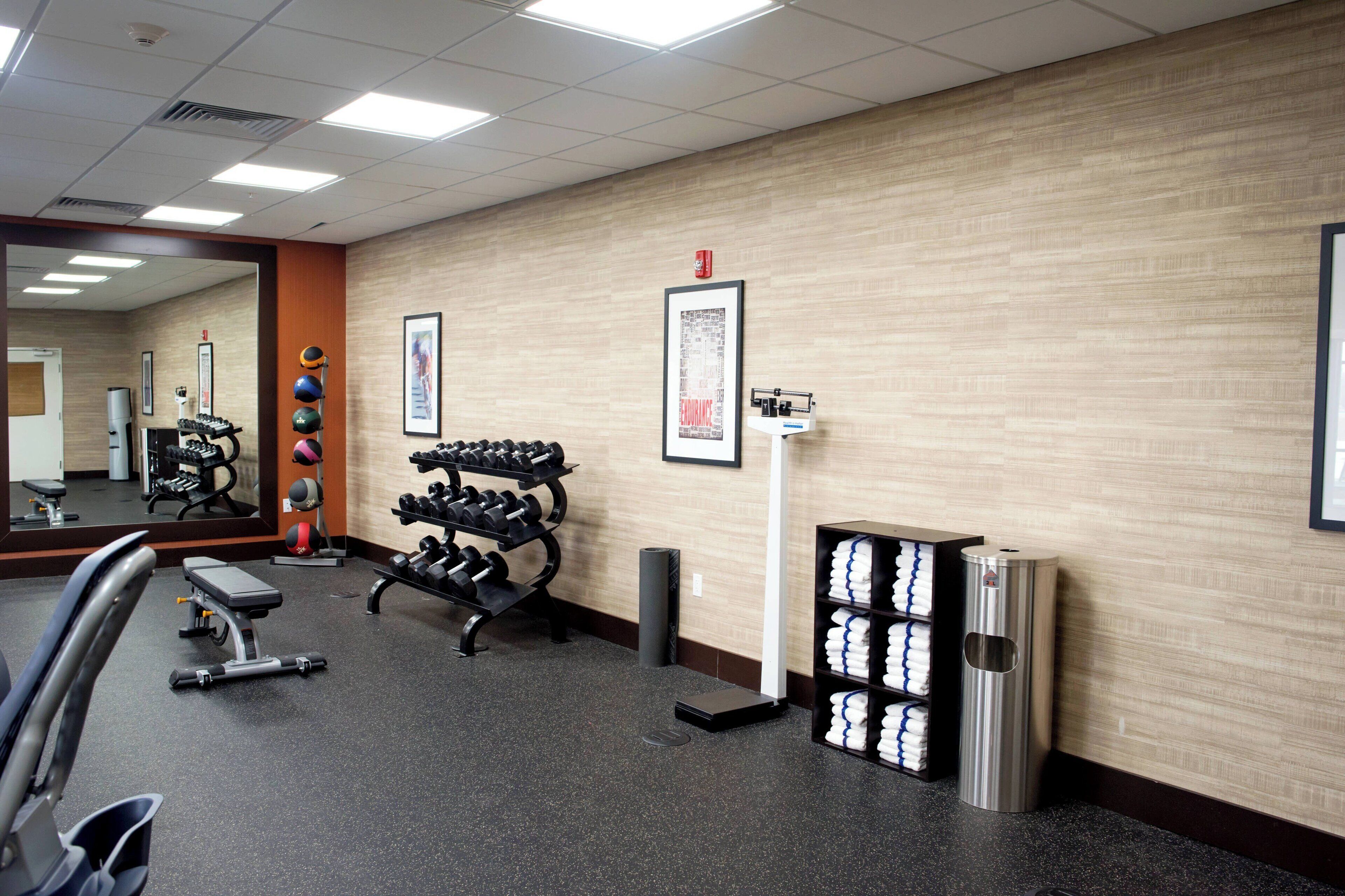 A gym with exercise equipment, a mirror, and a towel rack.