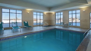 An indoor swimming pool with clear windows, chairs, and a view of the outside. - TownePlace Suites by Marriott Ames (Ames)