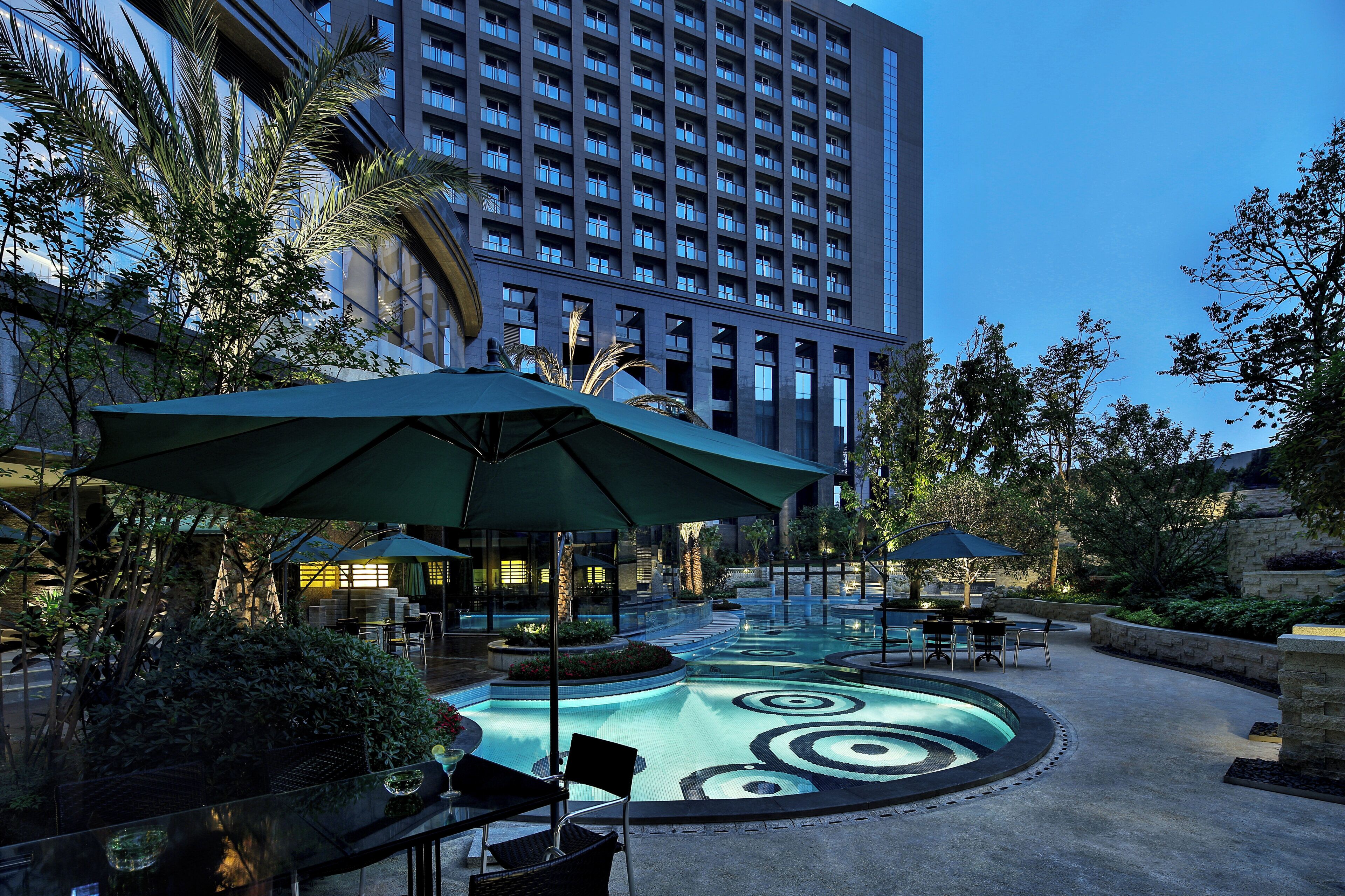 A pool area with umbrellas, seating, and a building in the background.