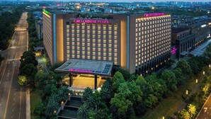 A hotel with a prominent "Crowne Plaza" sign, surrounded by lush greenery and a well-lit entrance.