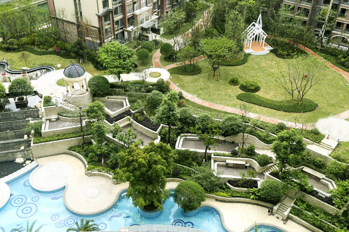A landscaped garden with a swimming pool, a gazebo, and a small bridge.