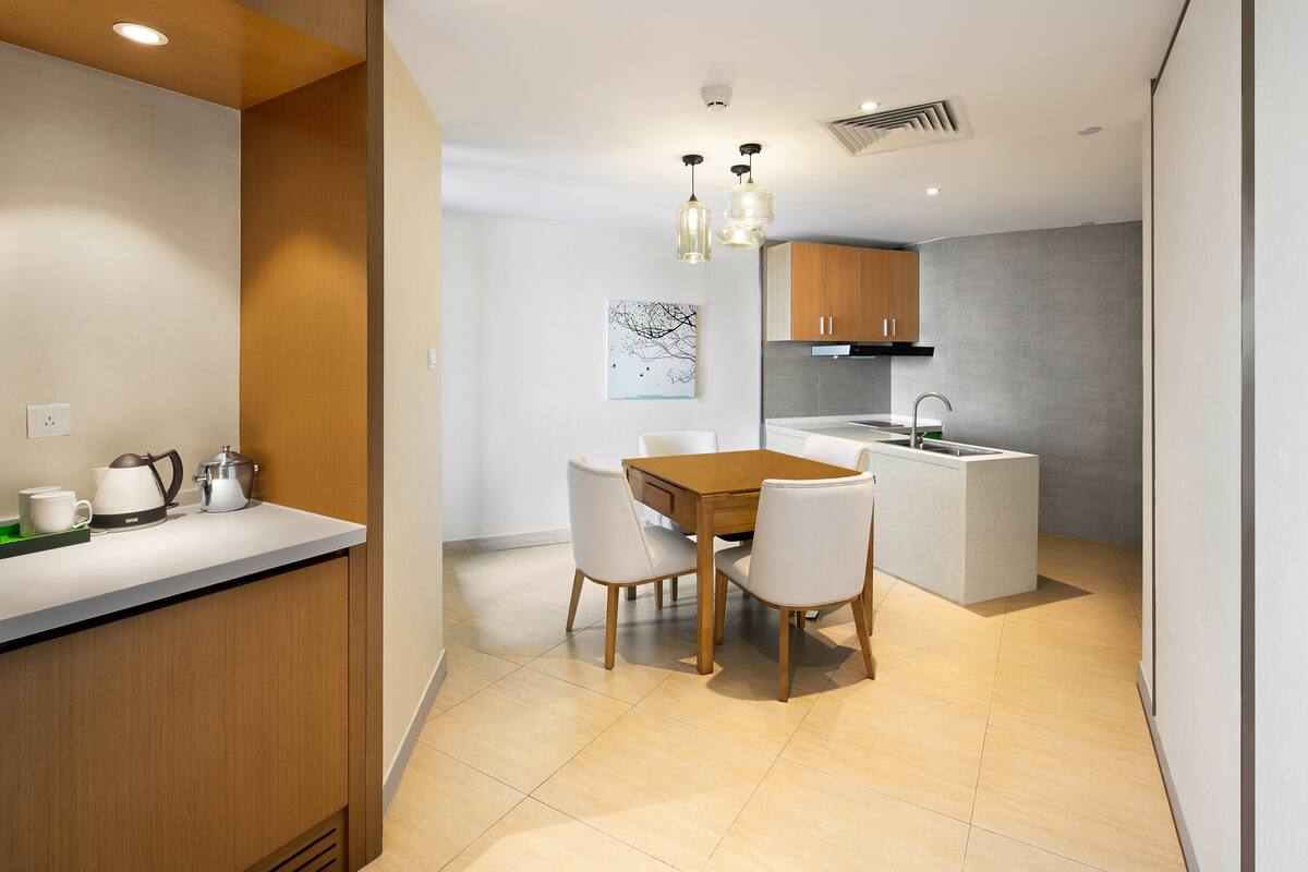 A modern kitchen with a wooden dining table and chairs, a built-in island, and pendant lighting.