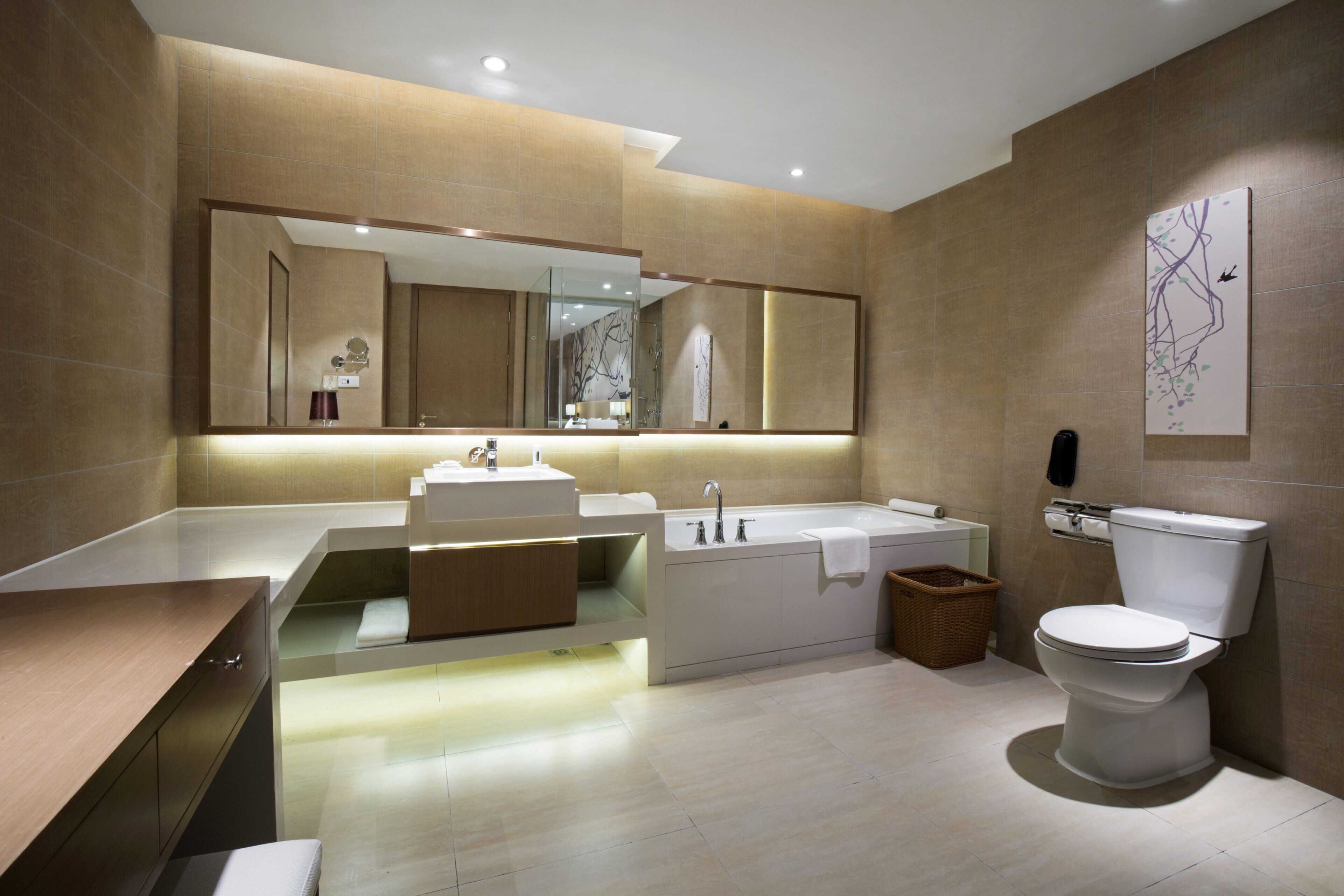 A modern bathroom with a large mirror, a bathtub, a toilet, and a vanity with a sink.