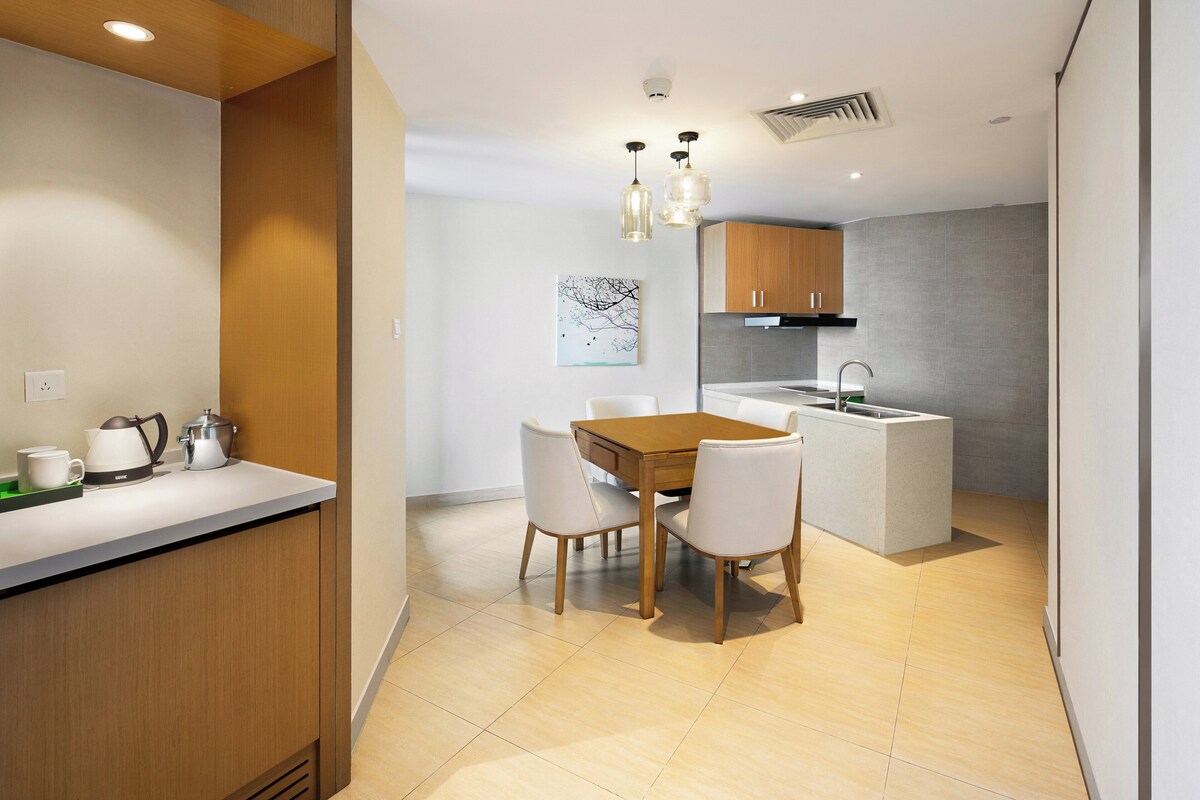 A modern kitchen with a wooden dining table and chairs, a built-in island, and pendant lighting.