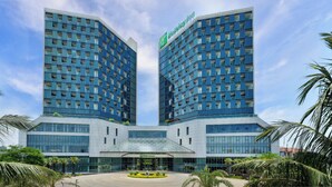 A modern hotel with two tall buildings featuring a grid of windows and a central entrance. - Holiday Inn Haikou West Coast by IHG (Haikou)