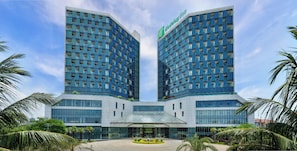 A modern hotel with two tall buildings featuring a grid of windows and a central entrance. - Holiday Inn Haikou West Coast by IHG (Haikou)