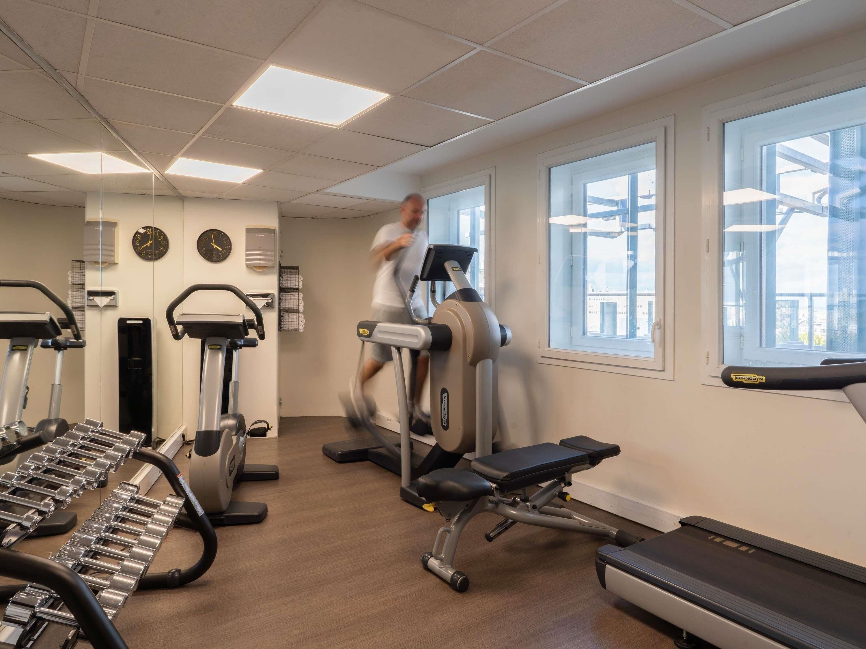A gym with treadmills, elliptical machines, and weight benches.