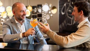 Two men toasting with drinks at a bar with a modern interior and abstract wall art. - Novotel Suites Paris Expo Porte de Versailles (Paris)