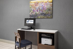 Un escritorio con computadora, una silla e impresora en una habitación de hotel.