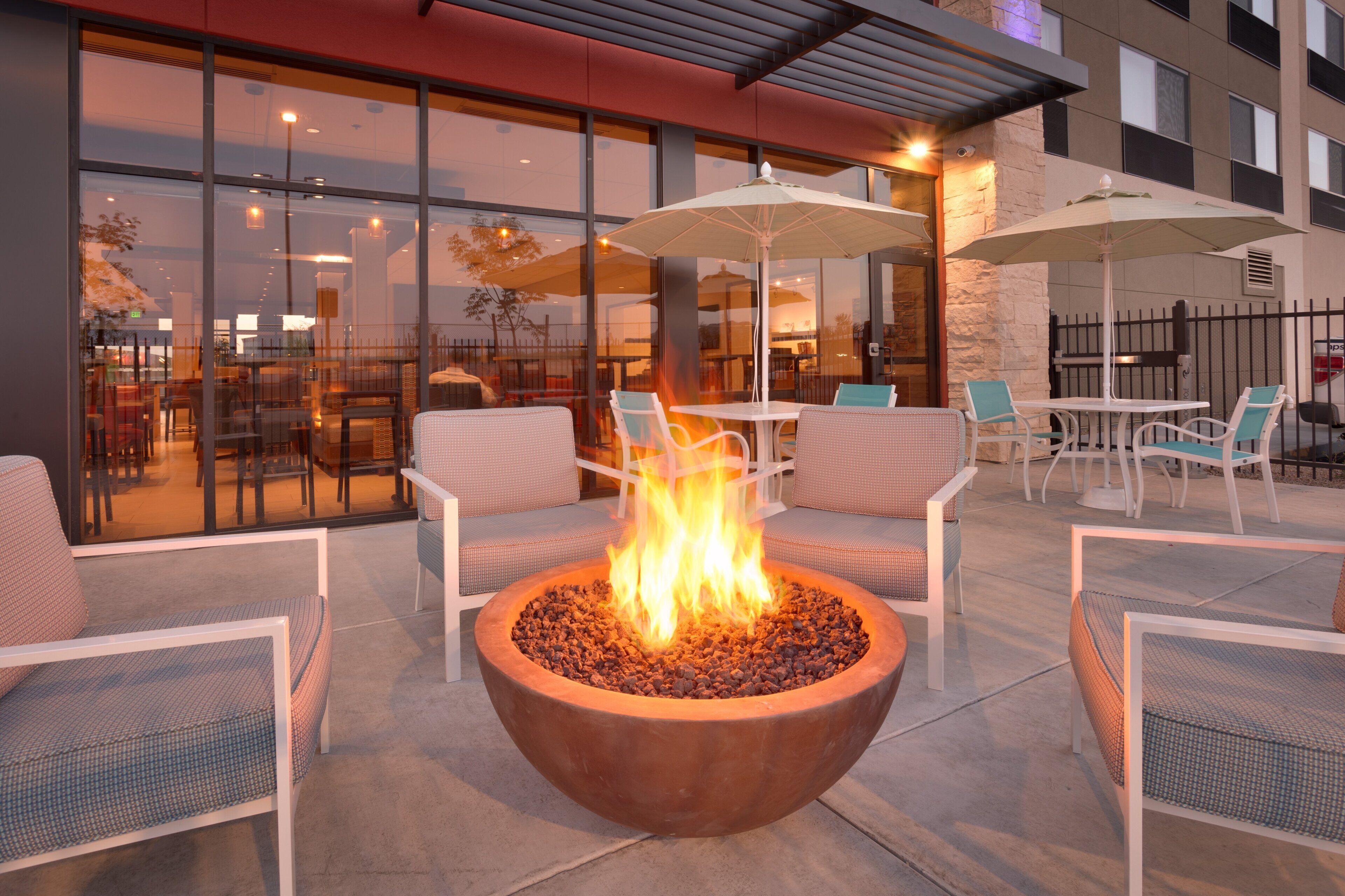 An outdoor seating area with a fire pit, tables, and chairs.
