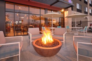 Un área de estar al aire libre con una chimenea, mesas y sillas.