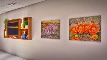 Una pared con tres cuadros enmarcados y una estantería de madera con adornos.