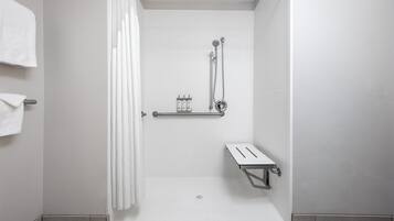 A shower area with a showerhead, a towel rack, and a shelf with toiletries.
