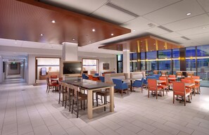 A modern hotel lobby with a dining area, a TV, and a view of the outside. - Holiday Inn Express & Suites Phoenix West - Buckeye by IHG (Buckeye)
