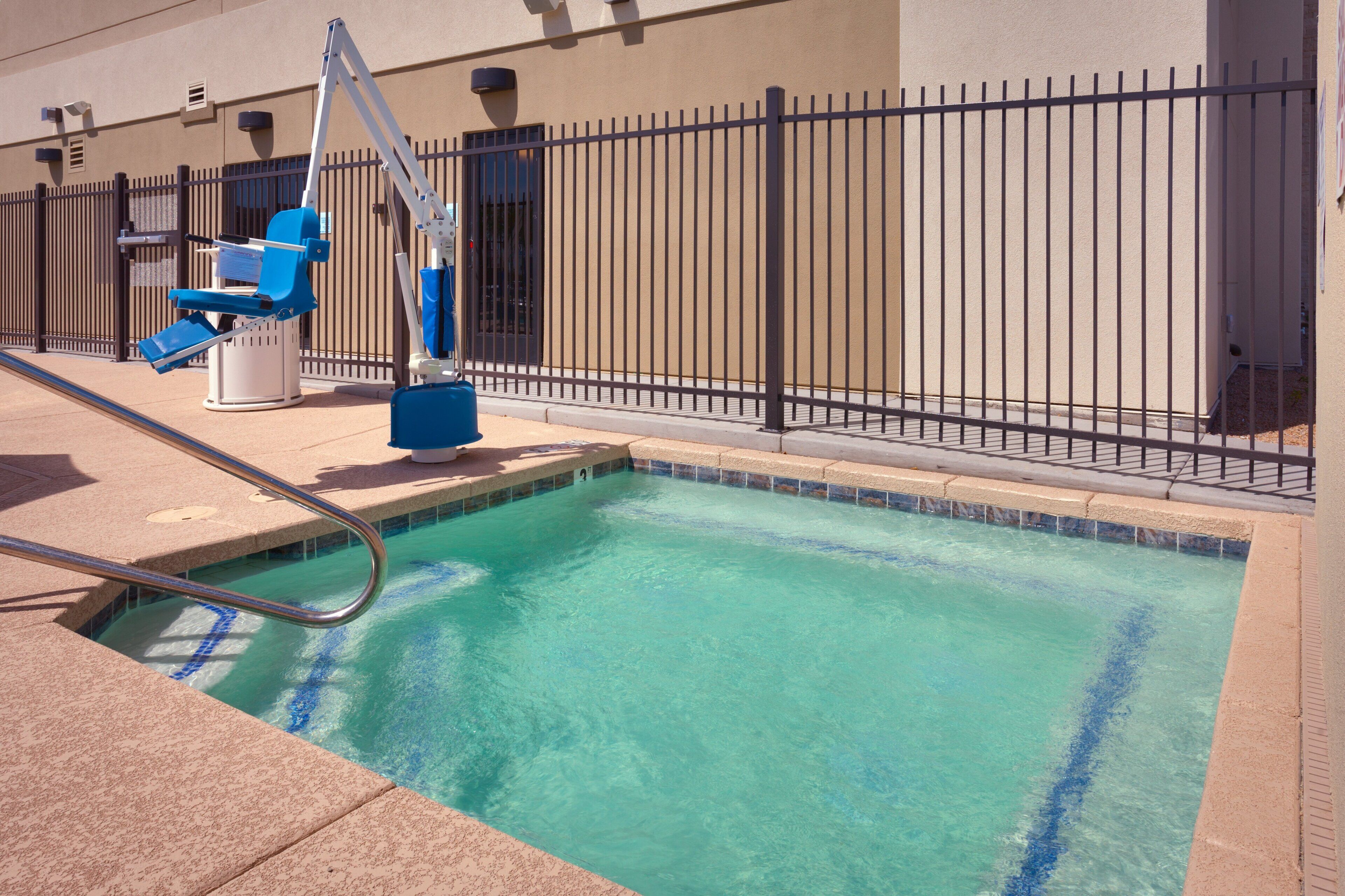 Piscina com escada de metal e cadeira salva-vidas azul.