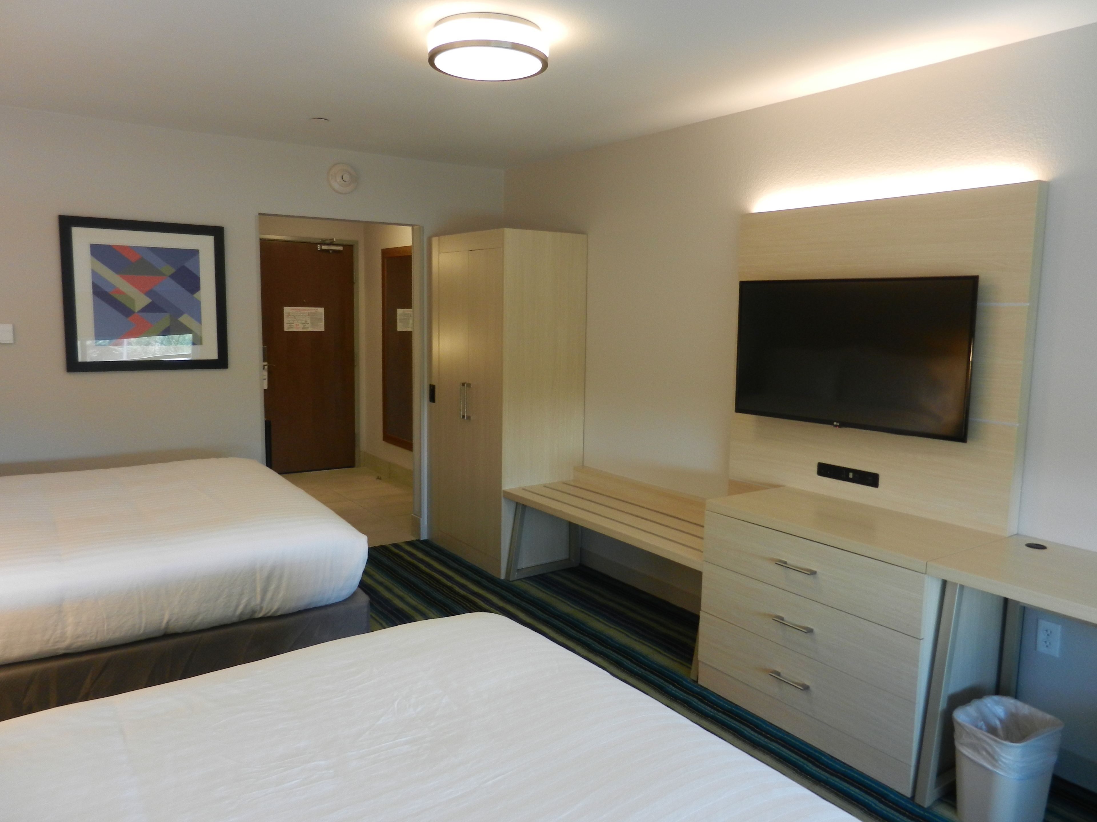Une chambre d’hôtel avec deux lits, une télévision, un bureau et une armoire.