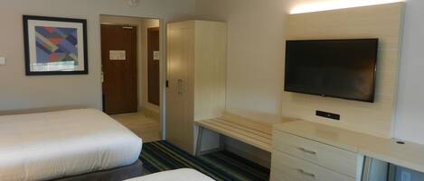Une chambre d’hôtel avec deux lits, une télévision, un bureau et une armoire.
