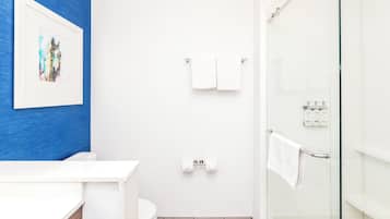 Un baño con inodoro blanco, cabina de ducha de vidrio y pared de acento azul.