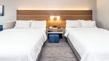 Une chambre d’hôtel avec deux lits, une table de chevet avec un téléphone et une horloge, et un luminaire fixé au mur.