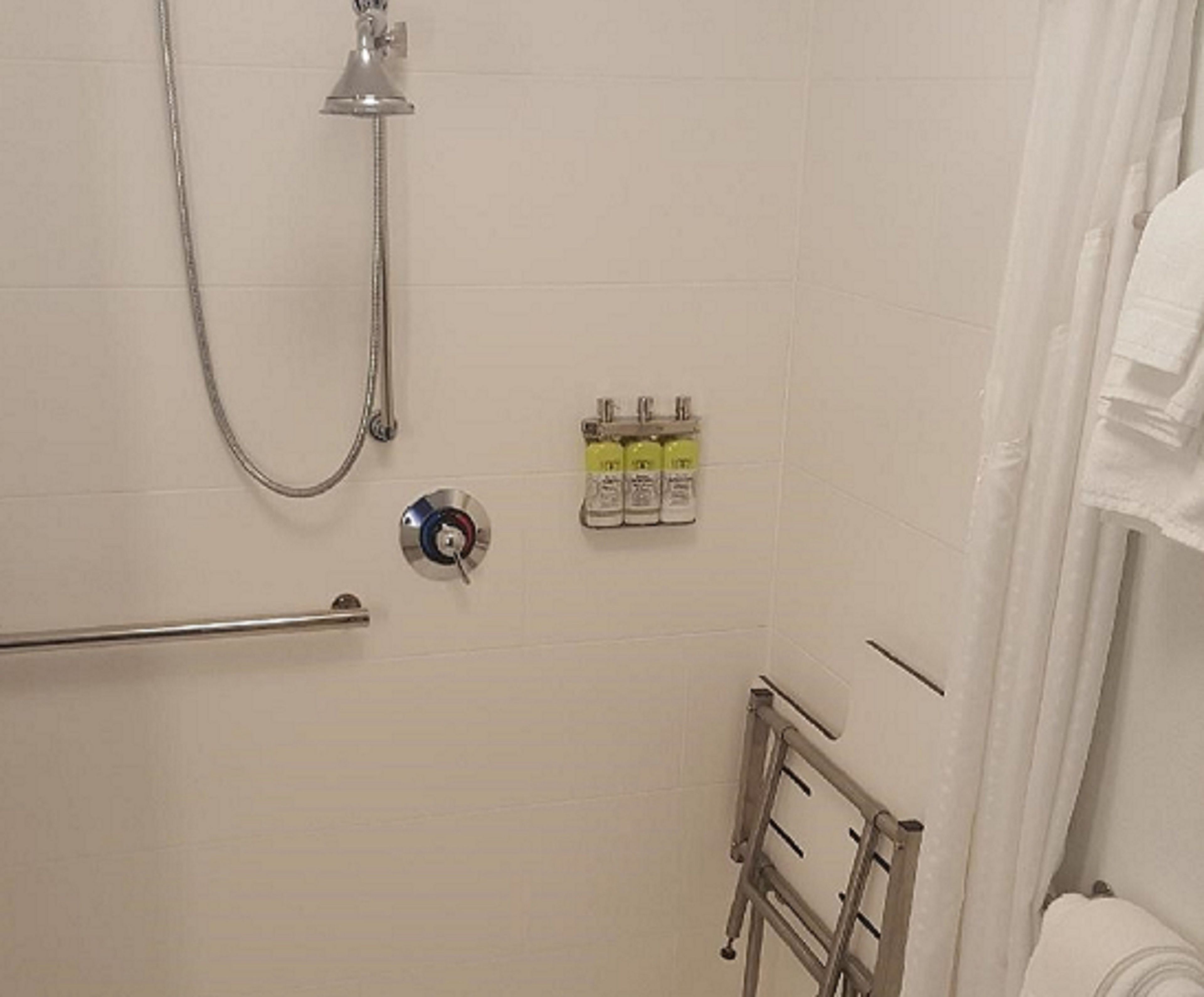 A bathroom with a shower, a towel rack, and a hand dryer.