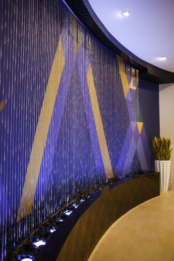 Un interior moderno con una pared curva que presenta líneas verticales y patrones geométricos.