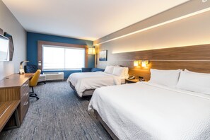 Une chambre d’hôtel avec deux lits, un bureau, une chaise, une fenêtre et une lampe.