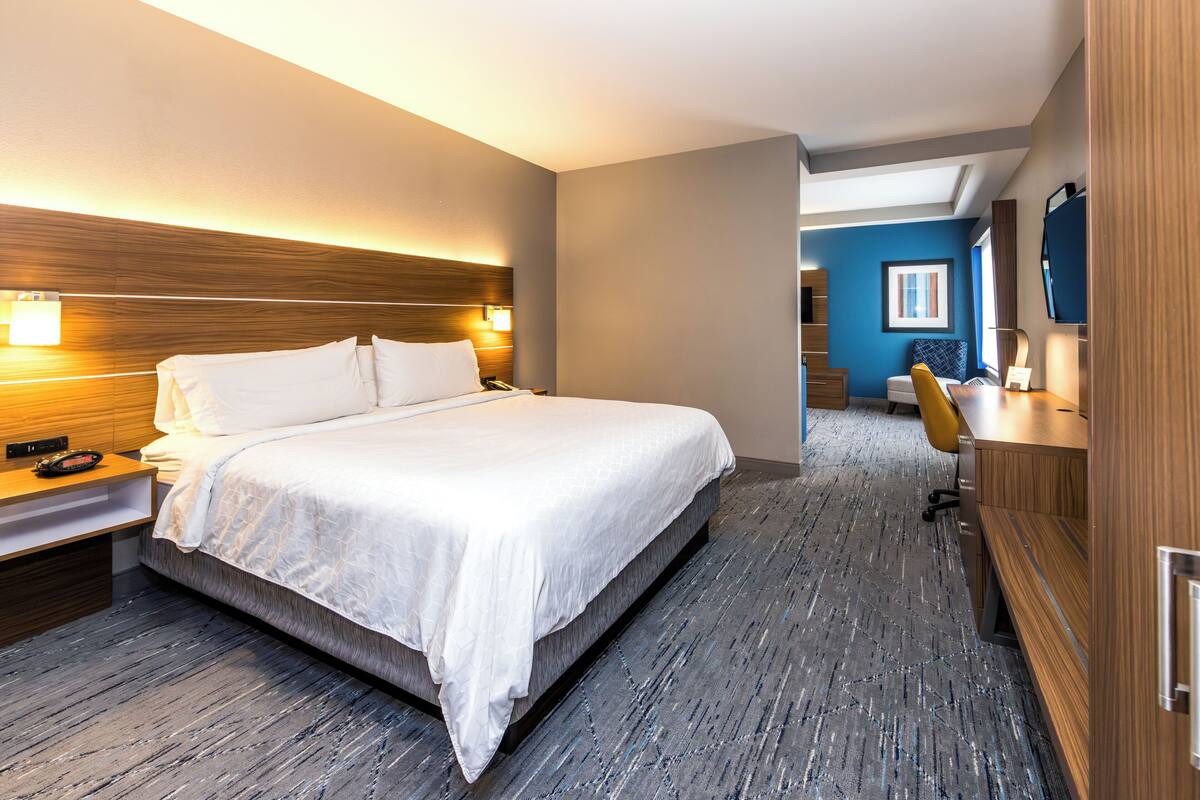 Ein Hotelzimmer mit einem großen Bett, einem Nachttisch und einem Schreibtisch mit Stuhl.