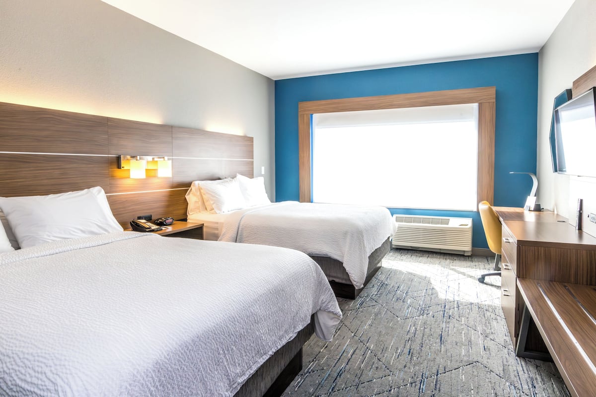 Ein Hotelzimmer mit zwei Betten, einem Schreibtisch und einem großen Fenster.