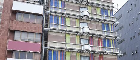 A multi-story hotel with a prominent 'Grand Frisa' sign, a brick facade, and a modern design with colorful window patterns.
