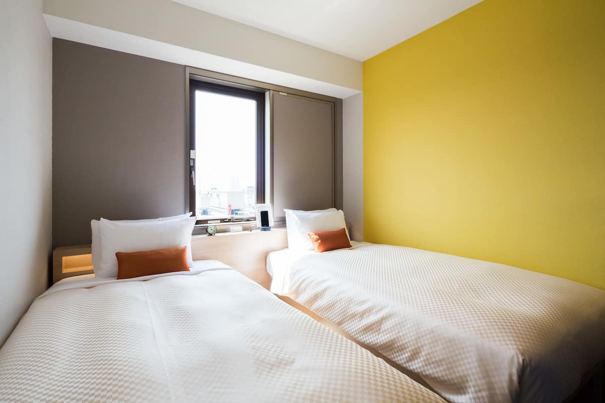 Een hotelkamer met twee bedden, een raam en uitzicht op de stad.