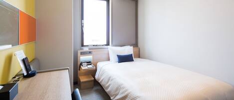 Una habitación de hotel con cama, mesita de noche y escritorio con teléfono y lámpara.