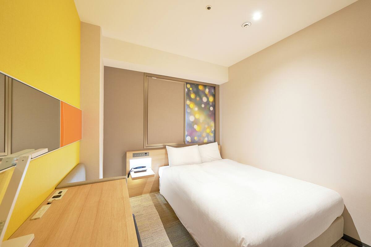 Een moderne hotelkamer met een bed, een bureau en een nachtkastje.