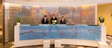 Una recepción con tres empleados, un diseño floral en el mostrador y un suelo estampado.