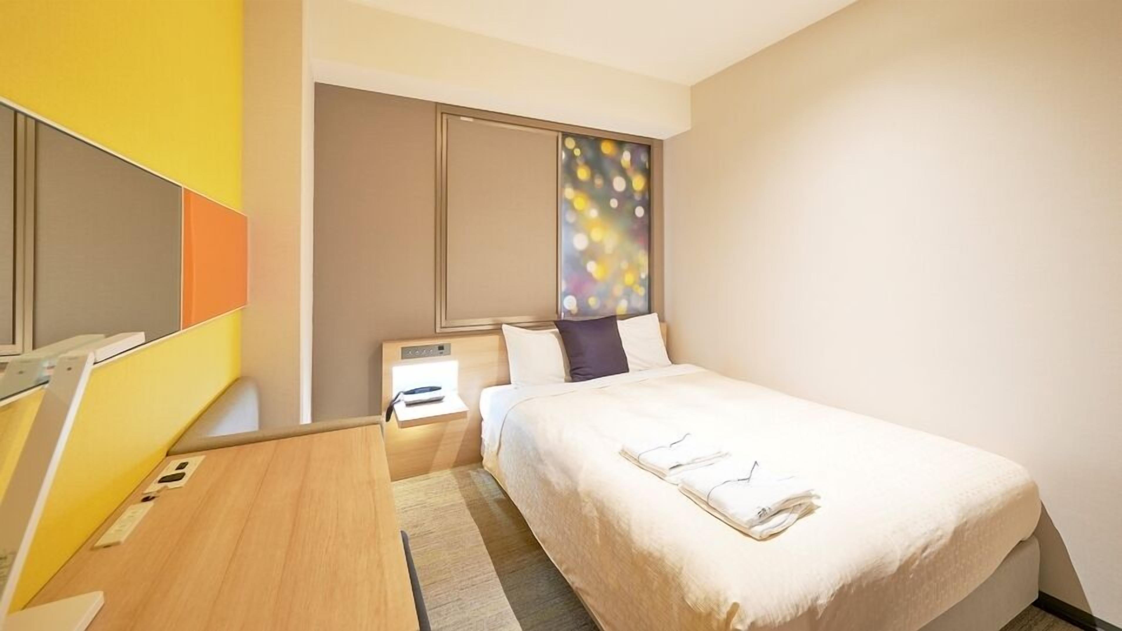 Une chambre d’hôtel avec un lit, une table de chevet et une grande fenêtre donnant sur un beau paysage.