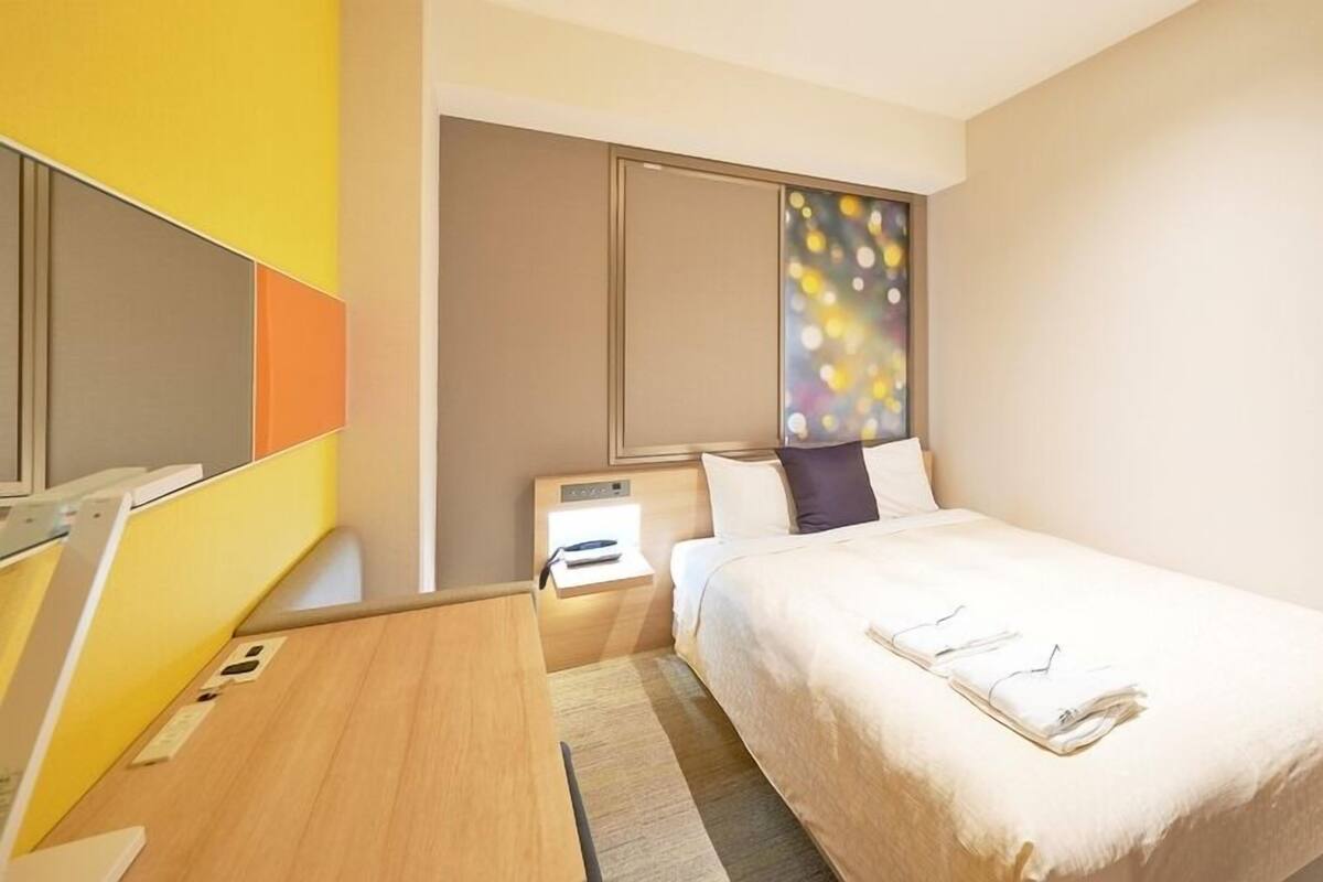 Een hotelkamer met een bed, nachtkastje en een groot raam met uitzicht.
