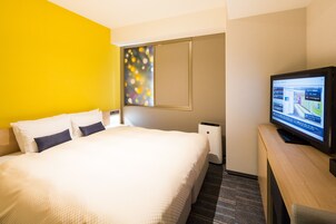 A hotel room with a bed, a television, and a wall-mounted screen displaying room information.