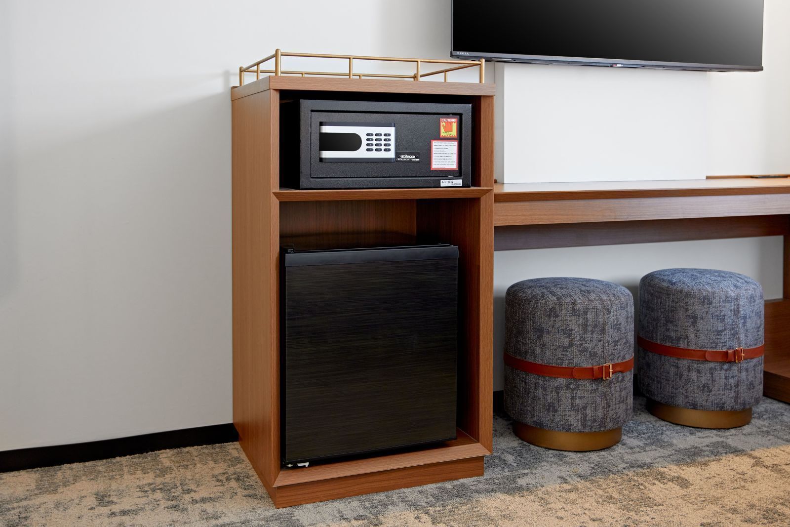 Una kitchenette compacta con microondas, refrigerador y dos otomanas.