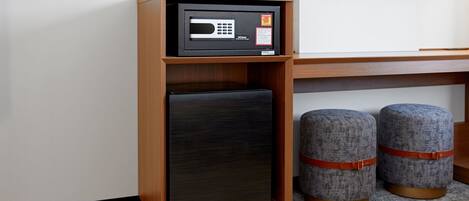 Una kitchenette compacta con microondas, refrigerador y dos otomanas.