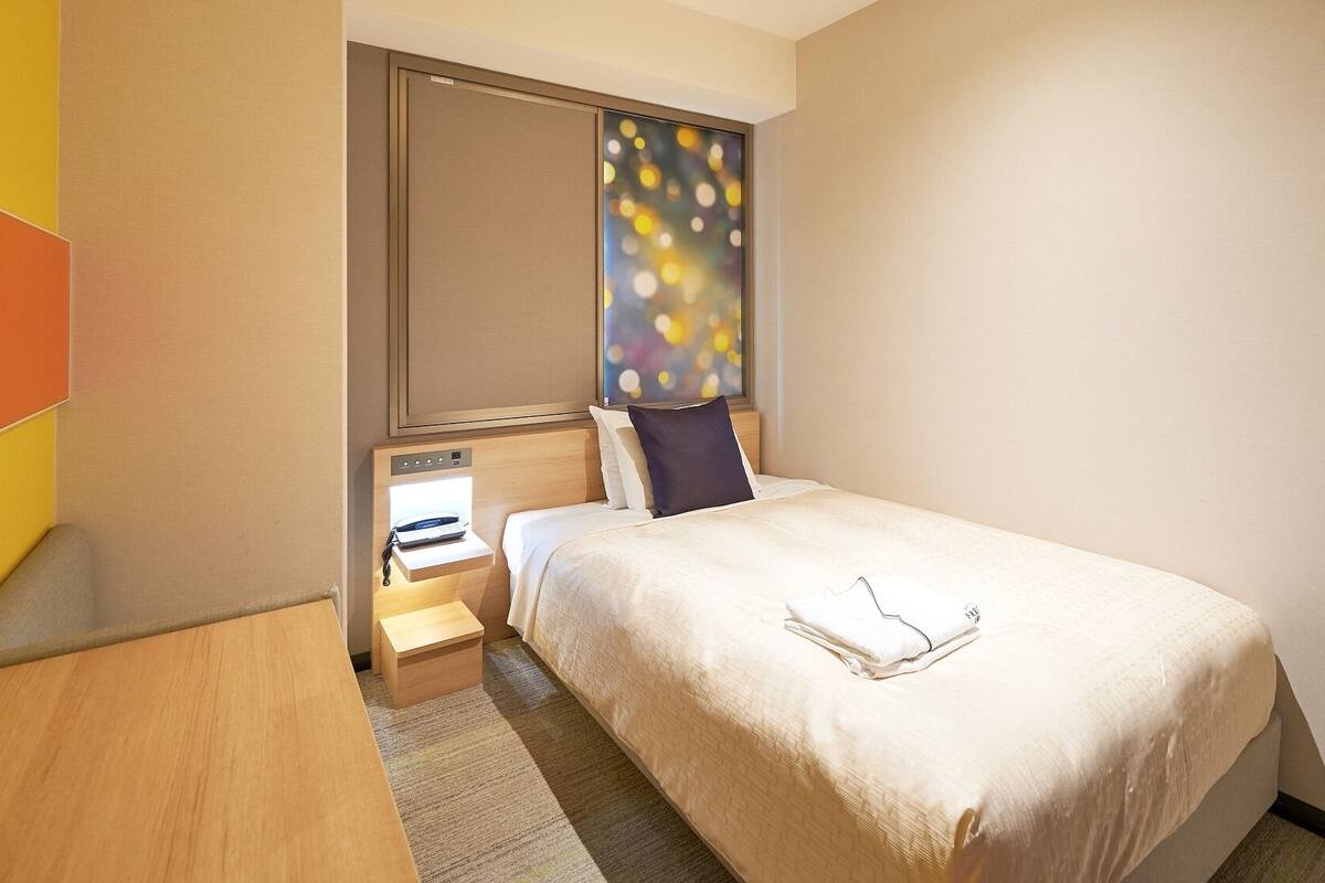 Een hotelkamer met een bed, nachtkastje en een raam met uitzicht.