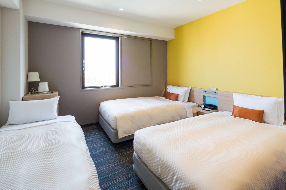Een hotelkamer met twee bedden, een raam, een bureau en een nachtkastje.