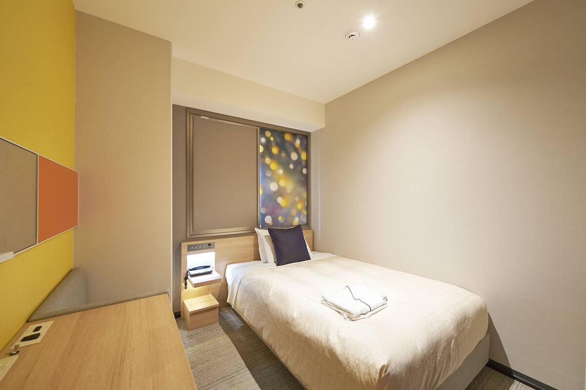 Een hotelkamer met een bed, nachtkastje en bureau.