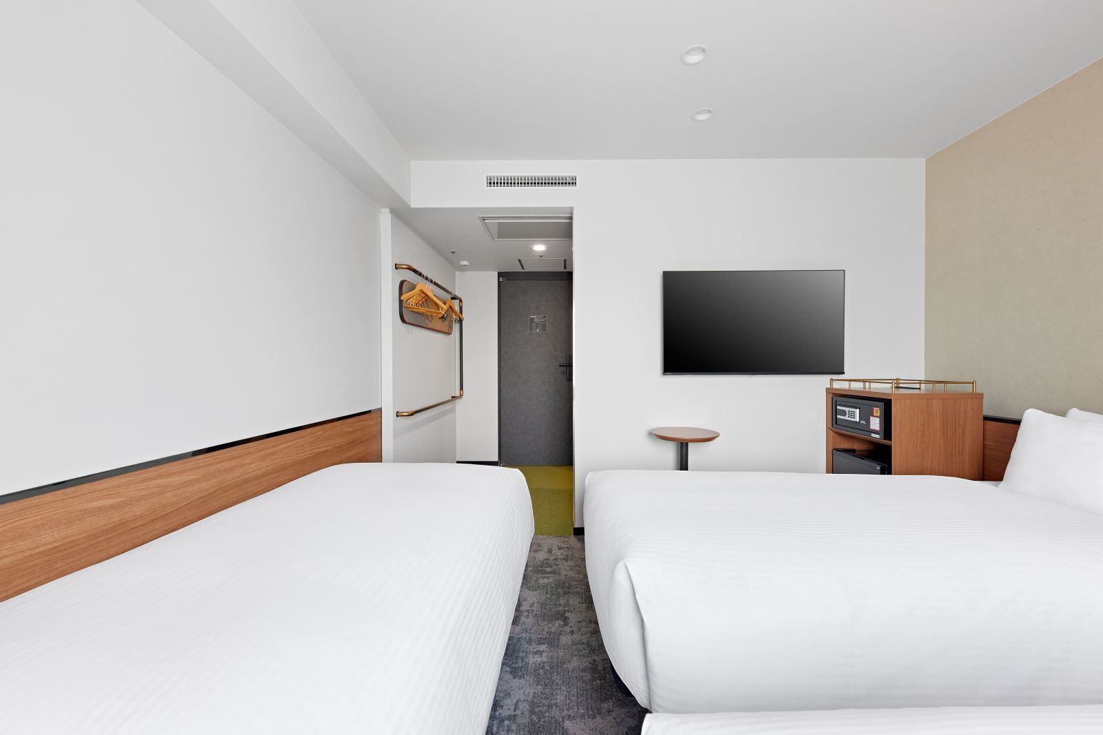 Een hotelkamer met twee bedden, een televisie, een tafeltje en een kledingkast.