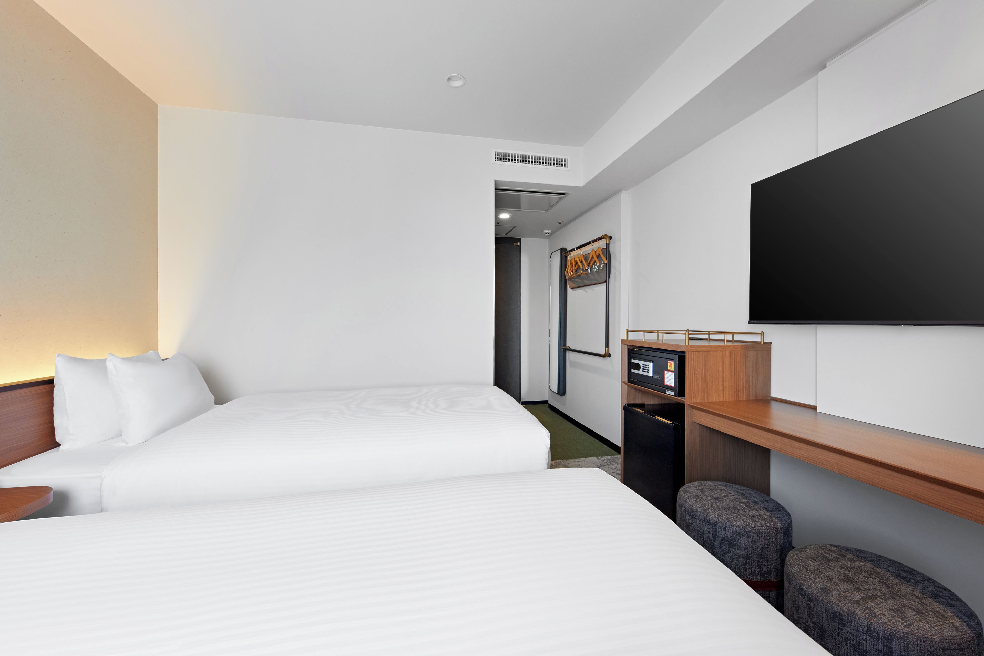 A hotel room with two beds, a desk, a flat-screen TV, and a seating area.