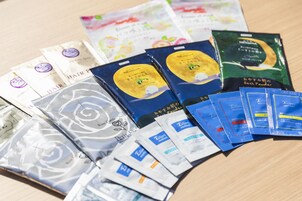 A variety of packaged products, including hair care items and bath powders, arranged on a wooden surface.