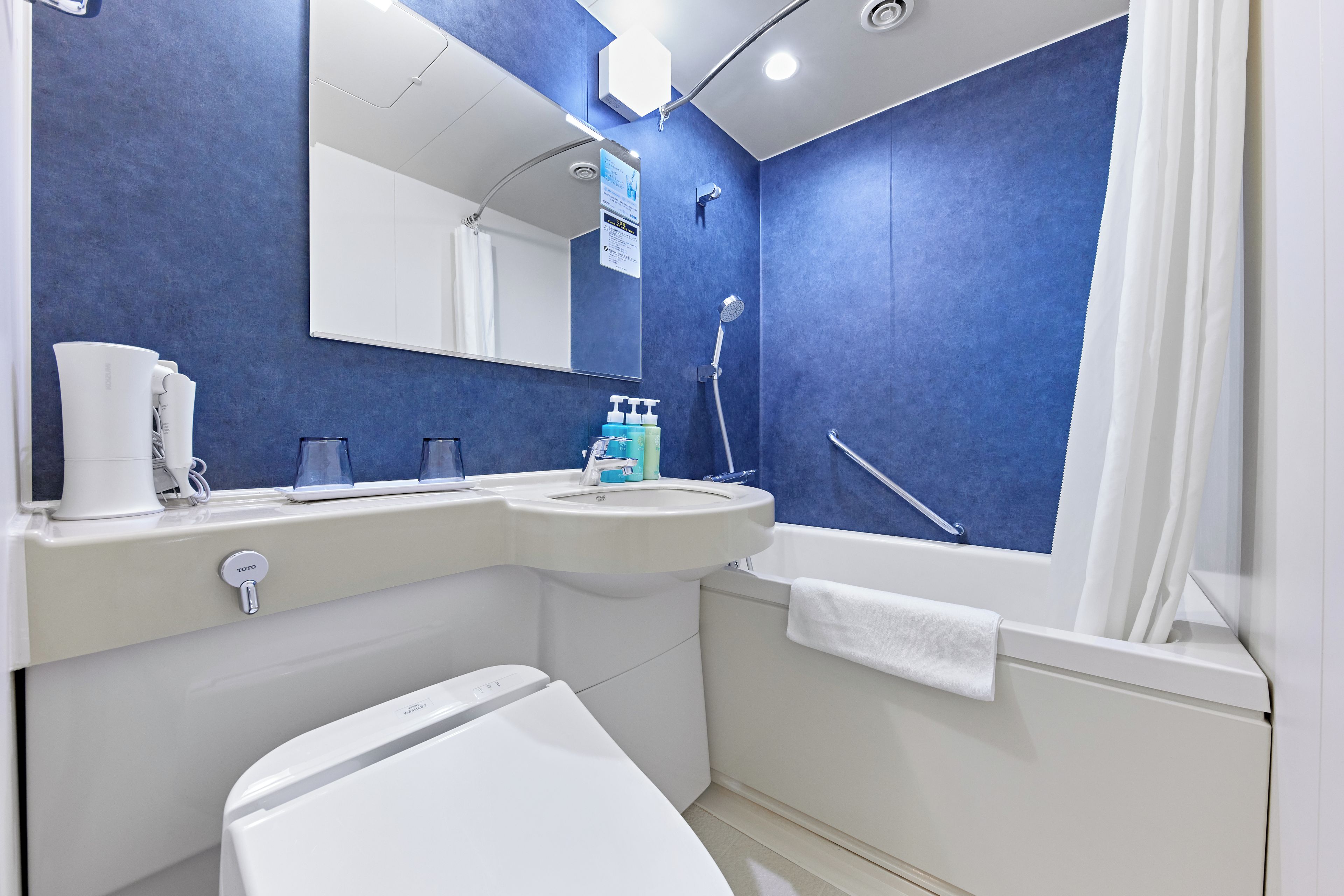 A modern bathroom with a white toilet, a sink, a mirror, and a shower area.