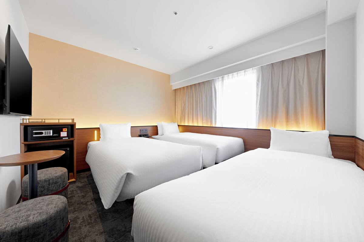 Een hotelkamer met twee bedden, een televisie, een bureau en een stoel.